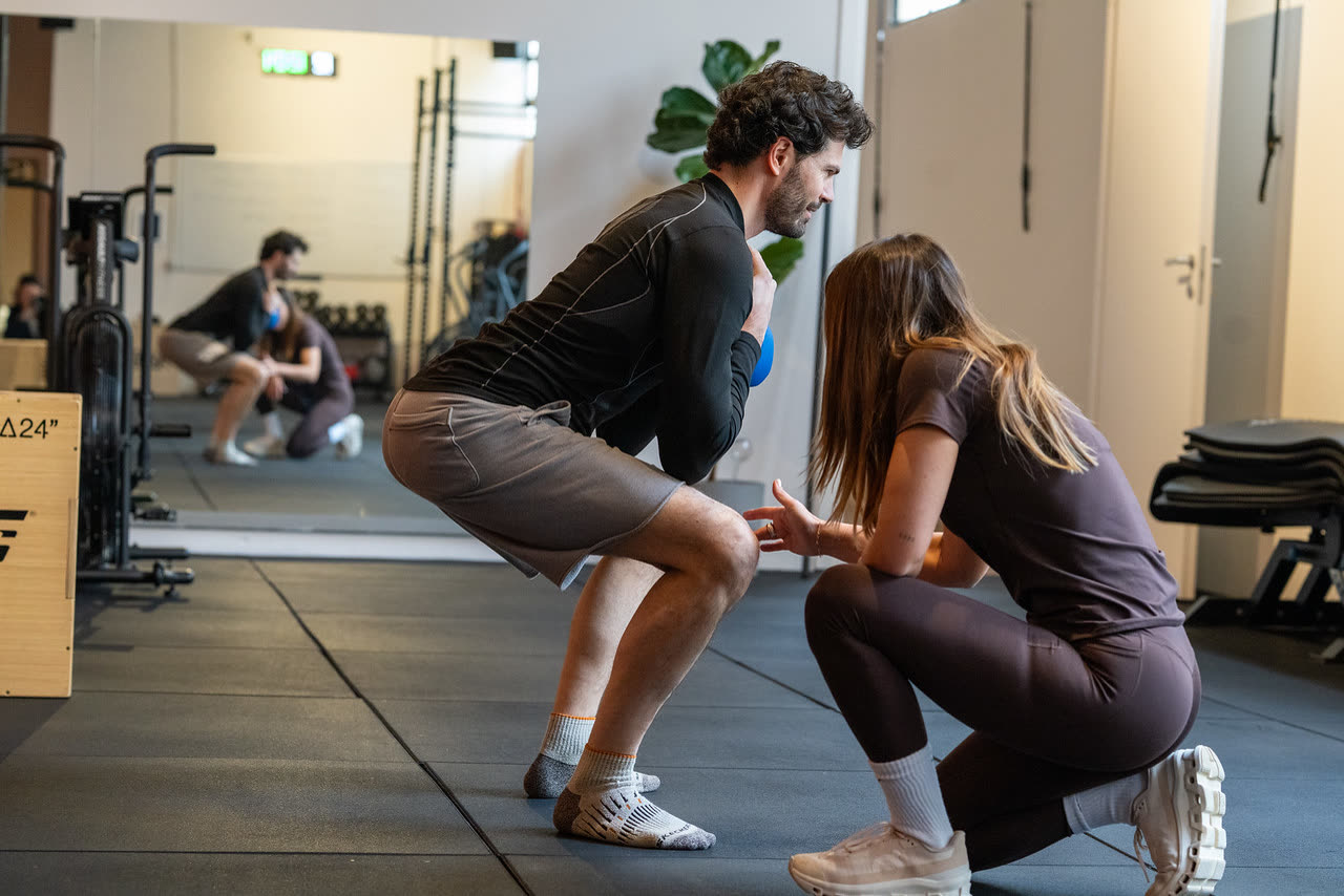 Coach Phil Lab assiste un cliente durante uno squat